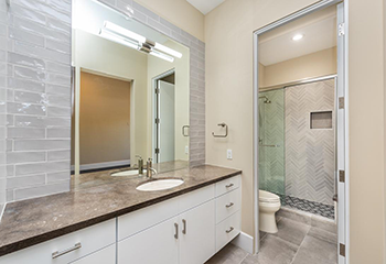 The image shows a newly remodeled bathroom featuring a modern shower with a glass enclosure.